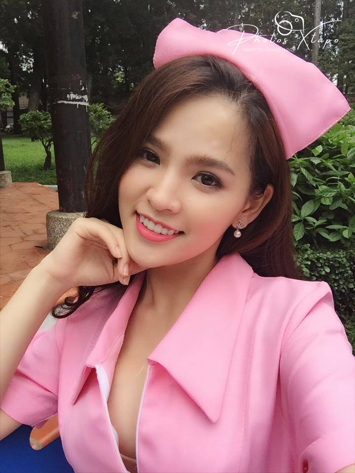 A young woman in a pink nurse's uniform smiles for the camera.