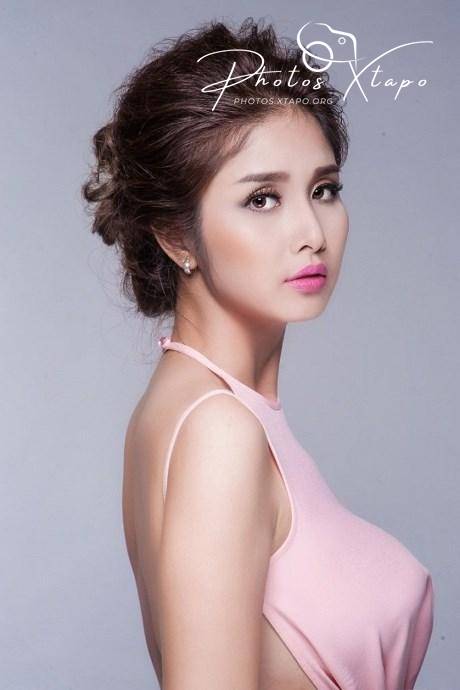 Portrait of a beautiful woman with her hair styled up, wearing a light pink halter-neck dress.  She is looking over her shoulder, creating an elegant and sophisticated feel.