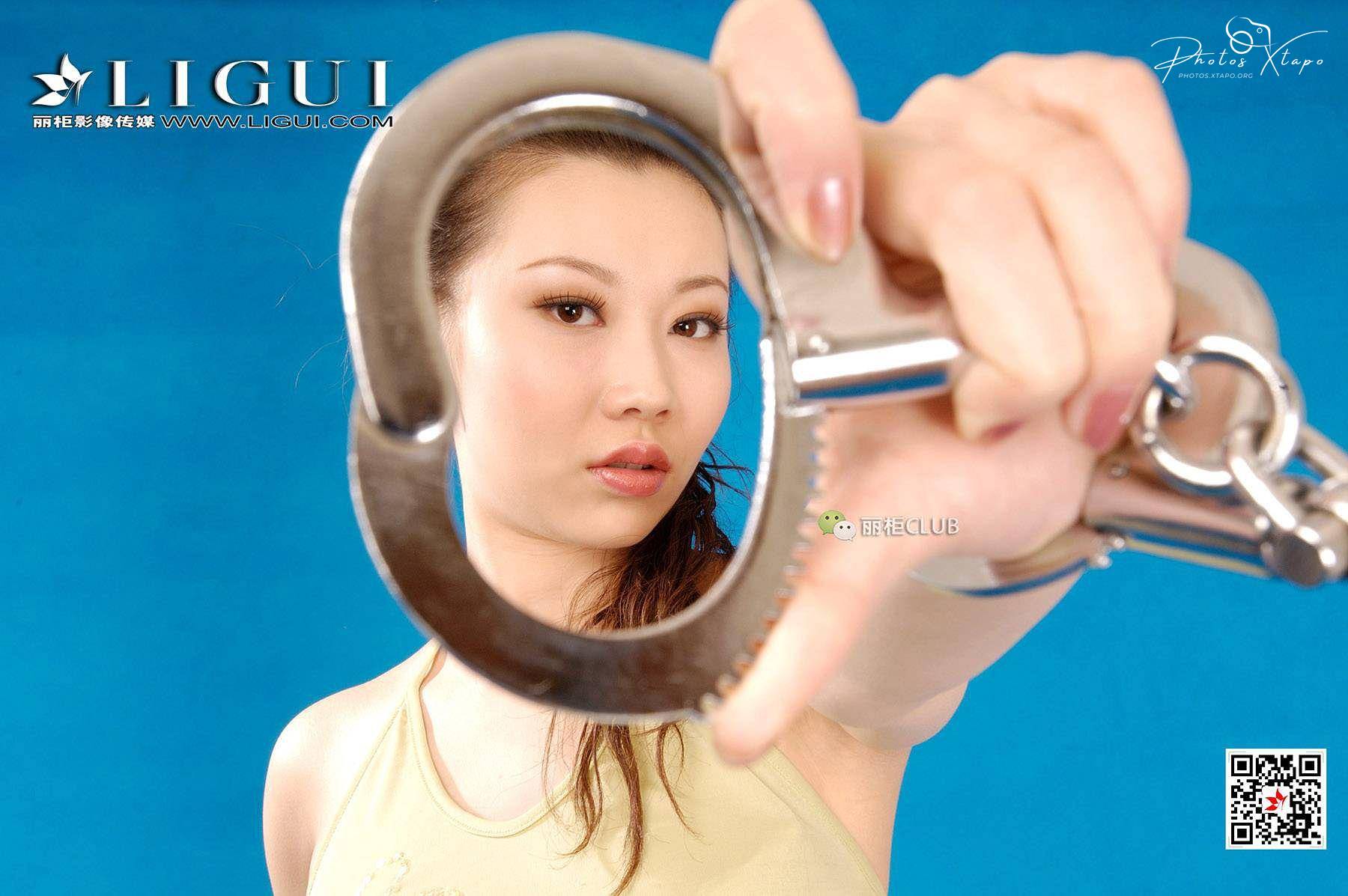 A woman playfully holds a pair of handcuffs in front of her face.