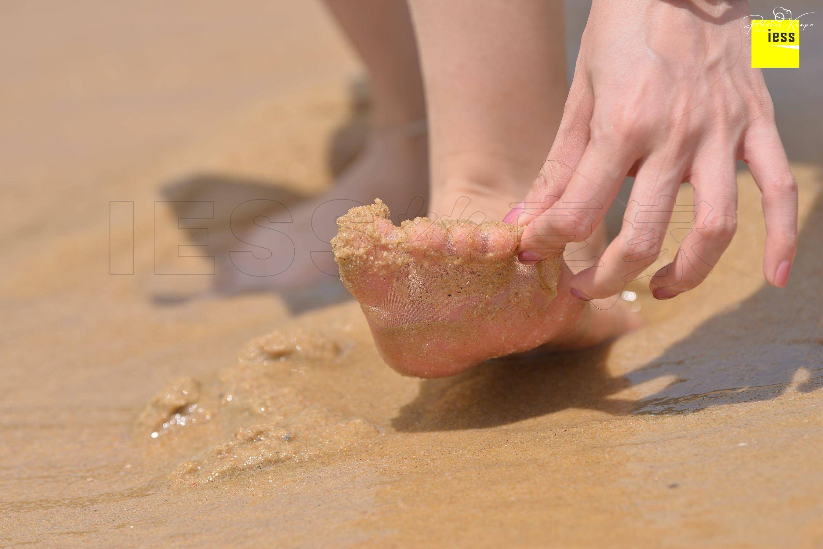 Close-up of a foot covered in sand on a beach.